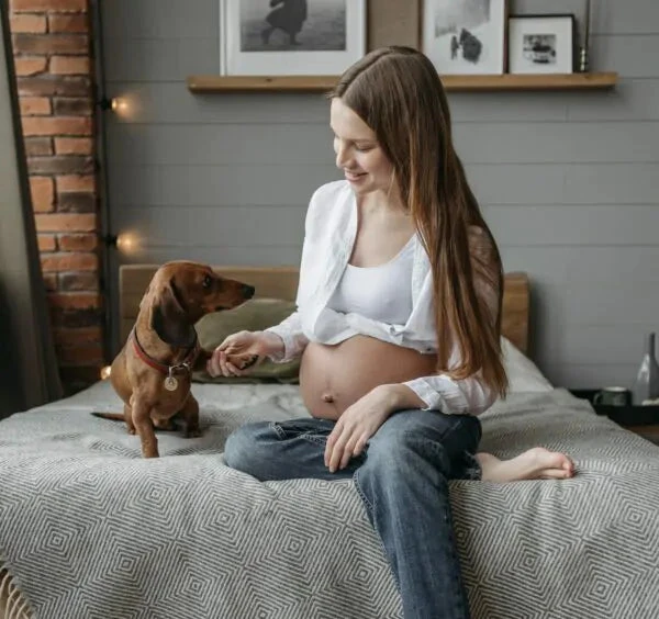 Těhotná žena se svým psem na posteli