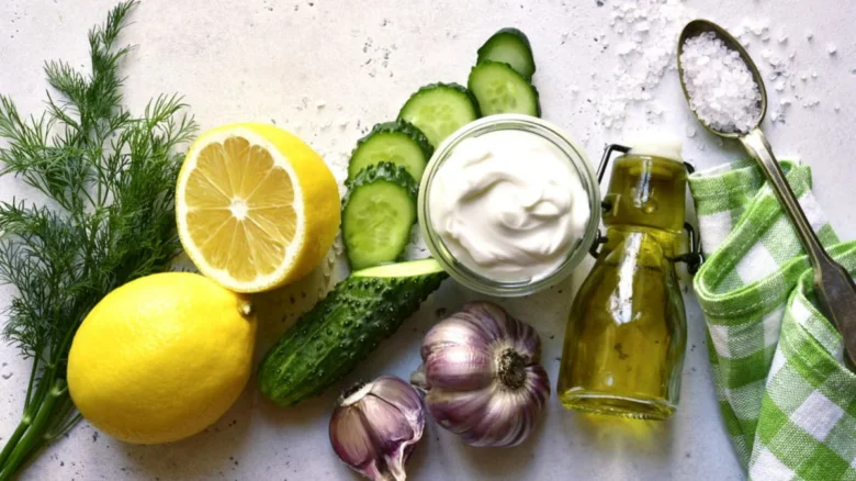 Suroviny pro domácí tzaziky: okurky, citrony, česnek, koprovina.