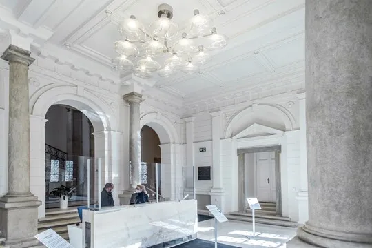 Jasný vstupní foyer s bílými sloupy a mramorovou recepcí.