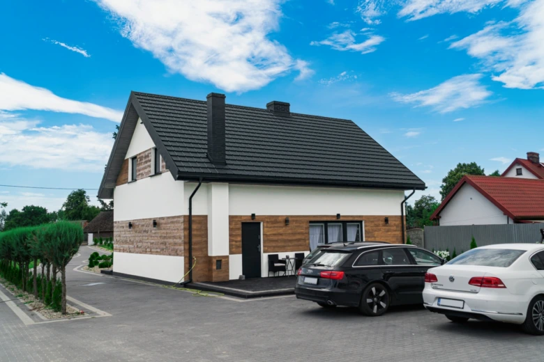 Moderní dům se šikmou střechou s tmavými taškami.