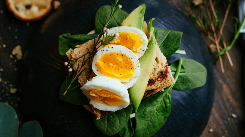 Svařené vejce nakrájené na toast s avokádem a špenát