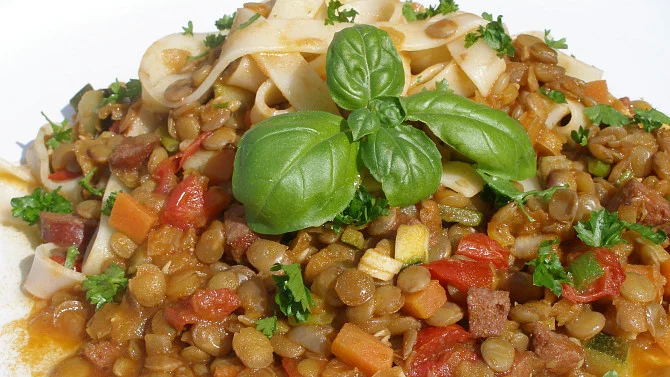 Pohled na talíř s čočkovým ragú naditými špagetami.