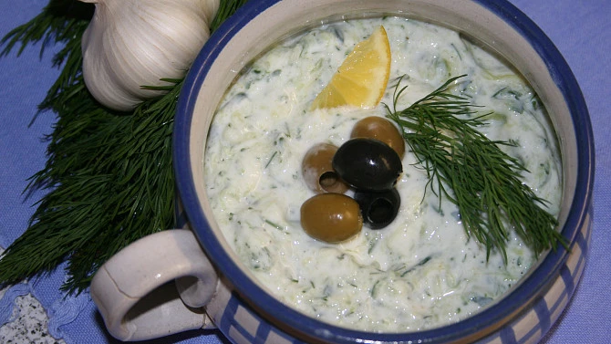 Miska s domácí tzazikou ozdobená olivami, citronem a koprem.