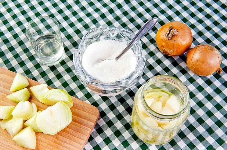 Nakrájená cibule na dřevěném prkénku s ingrediencemi.