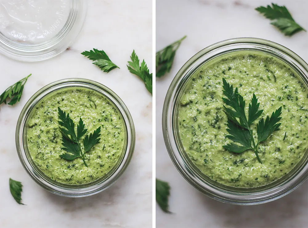 Sklenice petrželového pesto s čerstvou petrželem nahoře.