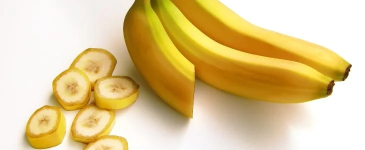 Žluté banány celé a nakrájené na bílém pozadí
