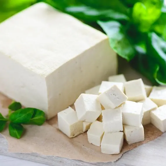Čerstvé bílé tofu s bazalkou na papíře.