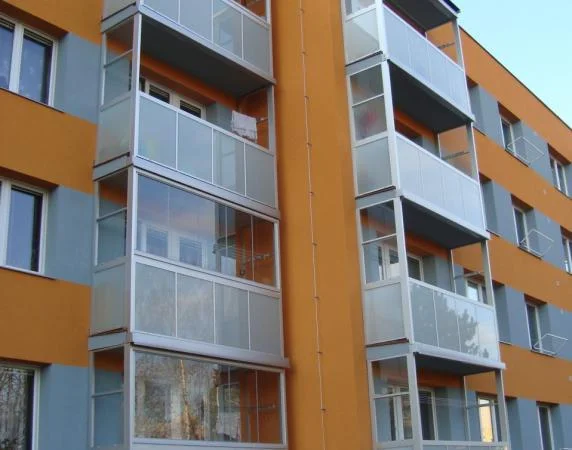 Nové skleněné balkony na fasádě bytového domu po rekonstrukci.