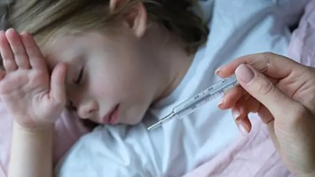 Dítě leží v posteli s teploměrem