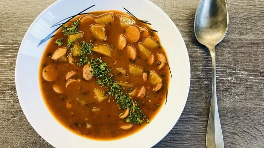 Bramborová kaše bez mléka v bílé misce s bylinkami.