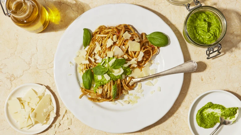 Pasta s čerstvou bazalkou a parmezánem na bílém talíři.
