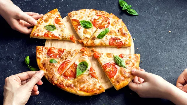 Čerstvá italská pizza s rajčaty, bazalkou a syrem na dřevěném podnosu.