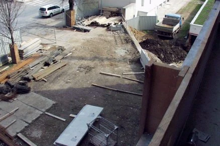 Staveniště s roztroušenými stavebními materiály a nákladním autem.
