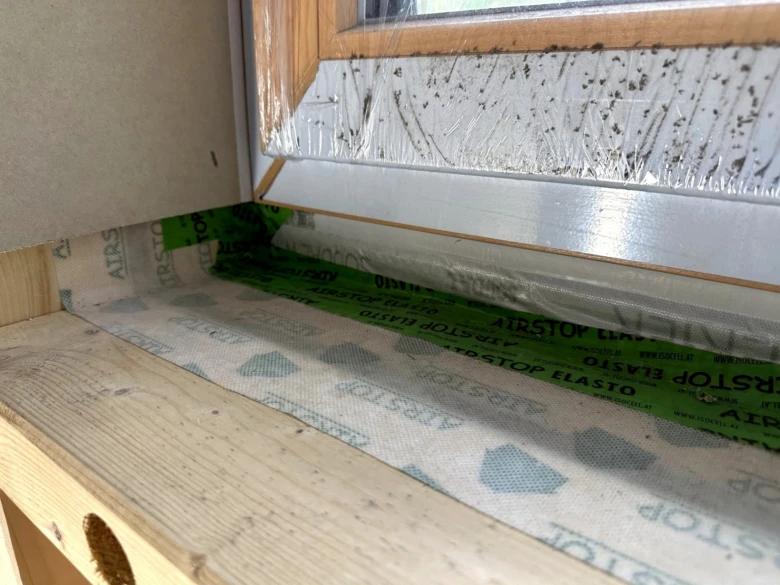 Detailní pohled na instalaci okna s aplikací izolační pásky.