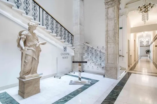 Velkolepý foyer s sochou, schodištěm a mramorovými sloupky.