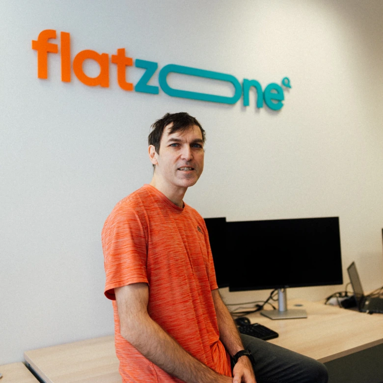 Muž sedící u počítače před logem firmy FlatZone.