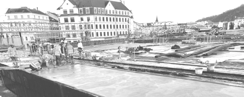 Stavební dělníci pracují na staveništi v historickém městském prostředí.