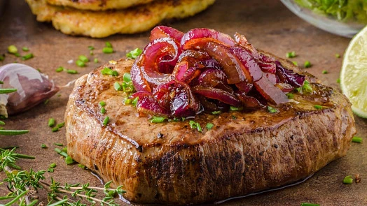 Grilovaný steak s karamelizovanou cibulí.