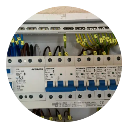 Otevřená elektrická rozvaděč s pojistkami a označenými vodiči.