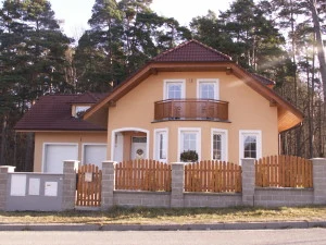 Dům s červenou šikmou střechou v přírodě.