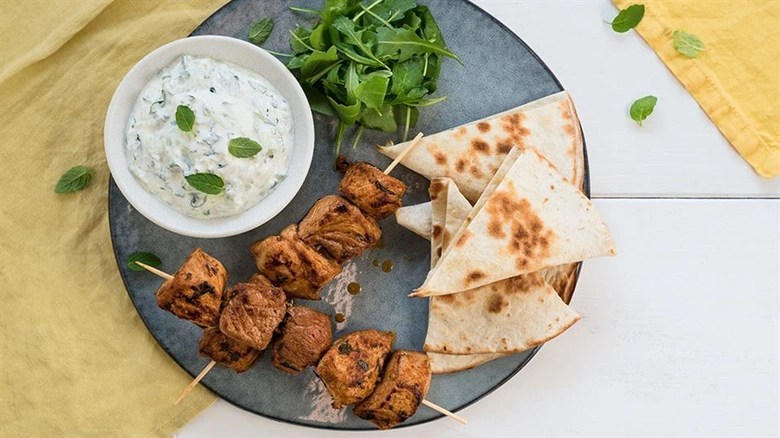 Grilled meat skewers served with pita and dip
