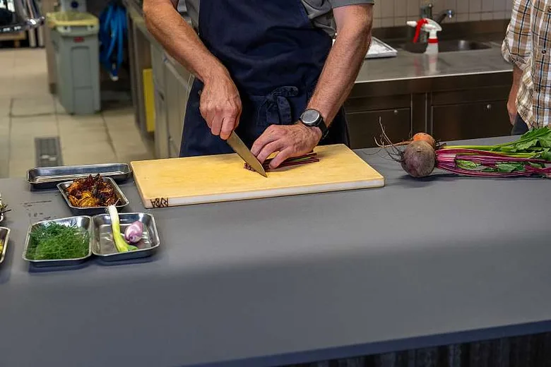 Kuchař řeže červenou řepu na dřevěné desce