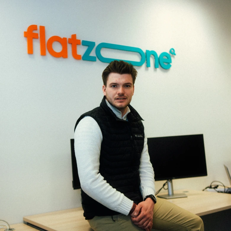 Muž sedí v kanceláři před logem firmy FlatZone.