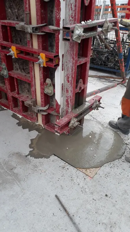 Utečící beton z forem na staveništi ukazuje problém s těsností.