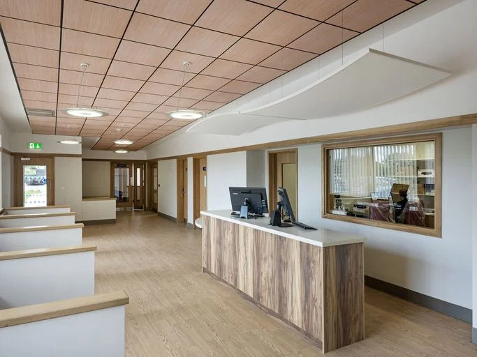 Moderní obchodní prostor s akustickými podhledy z dřevěných dlaždic.